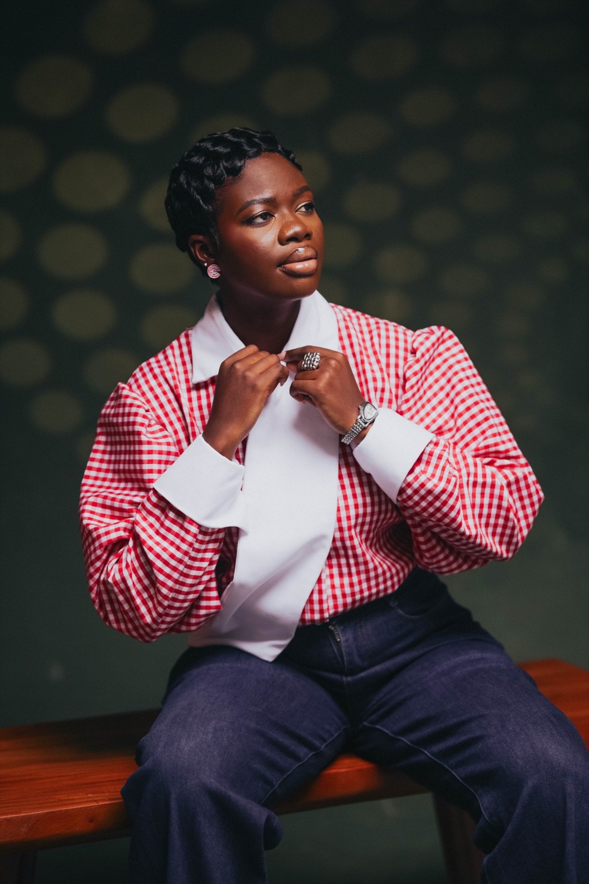 Mansa in a red gingham shirt, seated and looking into the distance